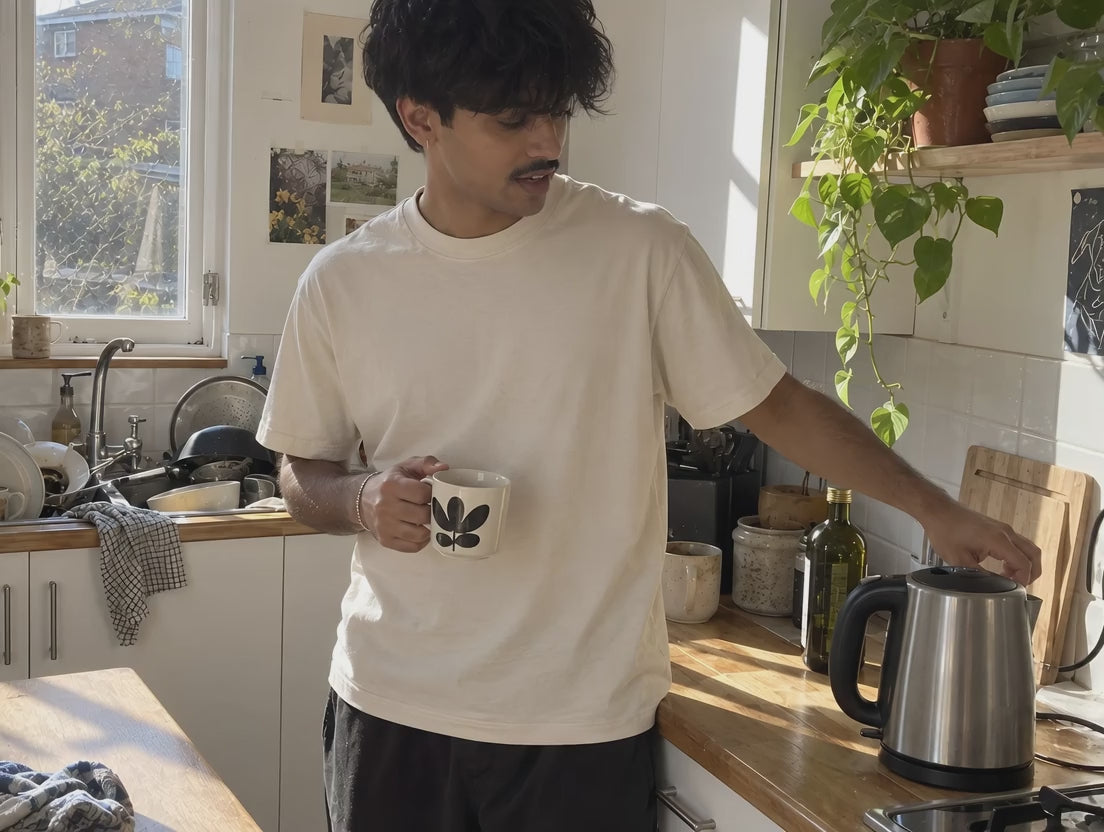 A man in the bone ENVY Lightweight Tee waiting on the kettle with a mug